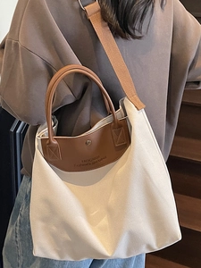 Minimalist canvas tote bag with brown leather trim and wide shoulder strap in daily use