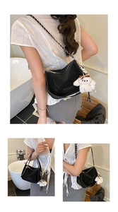 Detail view of black textured crescent bag with chain strap and plush puppy charm