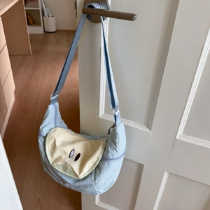Detail of light blue crescent bag featuring fruit embroidery on a beige canvas flap