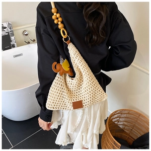 Detail of hand-woven crochet beach bag featuring large wooden bead strap and elephant charm