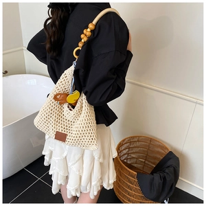Detail of hand-woven mesh beach bag with wooden bead strap and cute cartoon charm