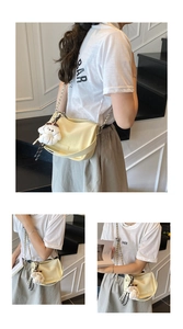 Detail of cream leather shoulder bag with zipper closure and white puppy plush keychain