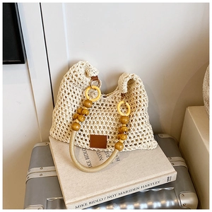 Detailed view of woven straw beach bag featuring unique beaded wood handles and leather patch
