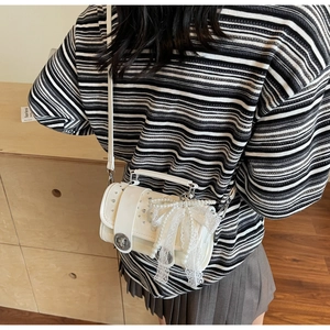 Detail of white PU leather bag with ornate pearl and lace bow decoration and turn-lock