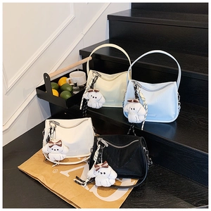 Detail shot of stylish PU leather handbags with plush puppy charms and printed scarves
