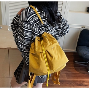 Dettaglio di una borsa a secchiello giallo acceso con coulisse e spalline regolabili