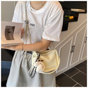 Detail of cream crossbody bag with soft leather texture and plush puppy charm