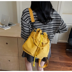 Dettaglio di una borsa a secchiello giallo brillante con coulisse e tracolla larga