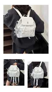 Detail of white backpack with silver star patterns featuring drawstring and magnetic flap