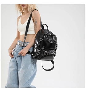 Detail shot of black patent leather gothic backpack with silver rings and cross charm