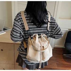 Dettaglio della borsa a secchiello in tela beige con chiusura a coulisse e tracolla