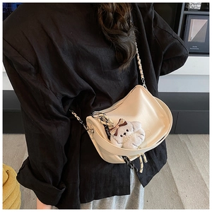 Détail du sac demi-lune crème avec pendentif chien en peluche et bandoulière en perles
