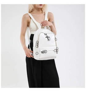 Detail view of a white punk backpack featuring black metal cross and rings decorations