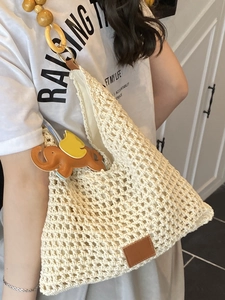 Chic cream woven beach bag with large wooden bead shoulder strap and elephant charm