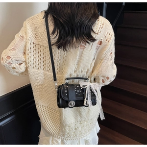 Detail of black crossbody bag featuring lace bow, pearl pendant and rhinestone clasp