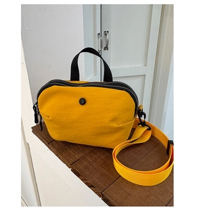 Détail d'un sac bandoulière en nylon jaune gingembre avec fermetures éclair noires