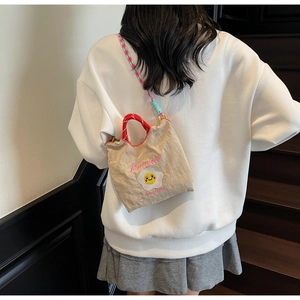 Dettaglio borsa a tracolla in nylon beige con ricamo a uovo fritto e tracolla in corda colorata