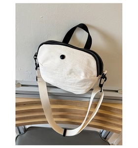 Détail du sac en nylon beige avec double fermeture éclair et bandoulière large