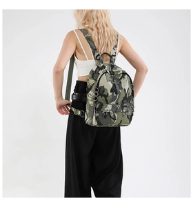 Close-up of camouflage punk backpack featuring metallic cross emblem and heavy rivets