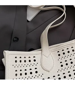 Détails des coutures renforcées et motif découpé au laser sur le sac cabas en cuir ivoire