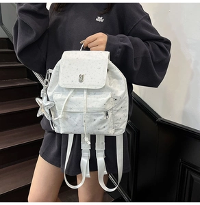 Close-up of white star pattern backpack with drawstring flap and silver star charm