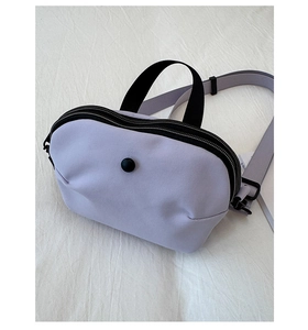 Vue détaillée de dessus d'un sac bandoulière en toile lilas avec double fermeture éclair