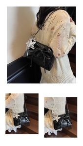 Close-up of black glossy leather bag with oversized bow and silver star pendant detail