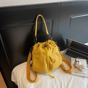 Dettaglio della borsa a secchiello in nylon giallo con trama impermeabile e design a pieghe