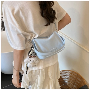Détail d'un sac sous les bras bleu clair avec un adorable porte-clés en peluche de chiot blanc
