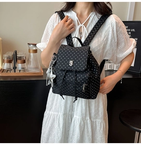 Detail of black mini backpack with white stars, drawstring closure and silver star charm