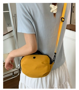 Détail d'un mini sac à bandoulière jaune vif avec fermeture éclair noire et sangle réglable