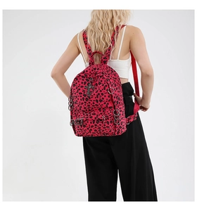 Detail of pink leopard print backpack with metal rings and cross pendant on model