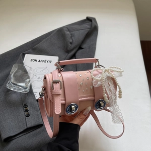 Detailed view of pink leather bag with pearl bow, lace ribbons and rhinestone accents