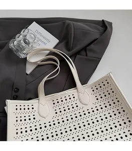 Détail des motifs ajourés au laser et de la texture du cuir sur un sac fourre-tout blanc