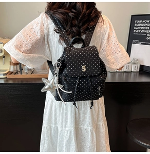 Close-up of black backpack with star pattern and silver star pendant in cafe setting