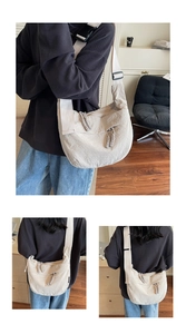 Detail of off-white dumpling bag showing pleated nylon texture and woven zipper pull