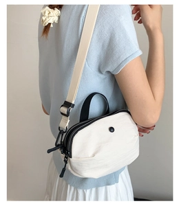 Détail du sac bandoulière blanc en nylon avec fermetures noires et sangle ajustable