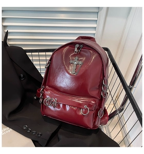 Detail of burgundy gothic backpack with metallic cross and silver chains in a cart