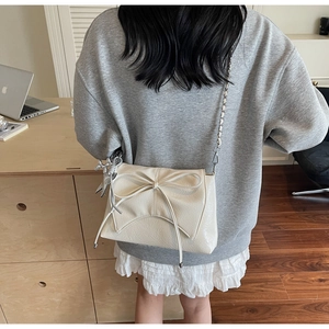 Close-up of ballet style bow bag with silver chain and cute rabbit charm on a model