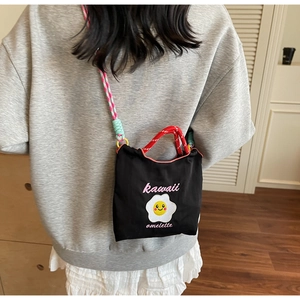 Dettaglio di una borsa a tracolla nera kawaii con cinturino in corda colorata e manico rosso