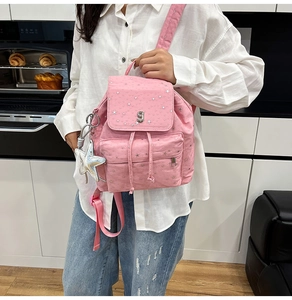 Close-up of pink backpack with silver star patterns, metal S logo and drawstring closure