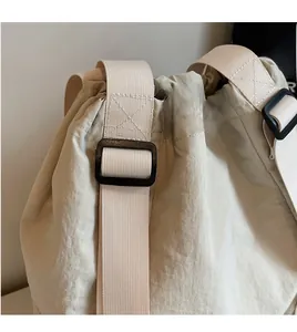 Detail of adjustable nylon strap and black plastic buckle on beige drawstring backpack