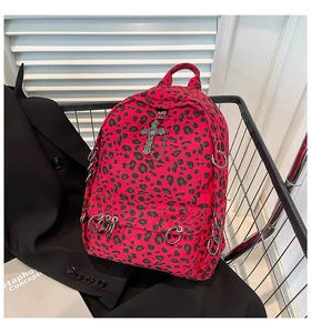 Close-up of red and black leopard print backpack with punk cross and metal ring details