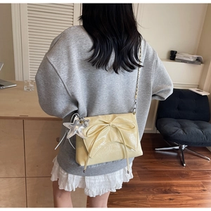 Detail of light yellow bow shoulder bag with silver star charm and metal chain strap