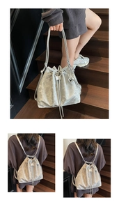 Detail of silver drawstring bucket bag with floral texture and butterfly metal charms