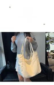 Close-up of large canvas tote bag in cream color with blue geometric letter print