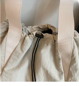 Detail view of durable drawstring opening and wide handles on the beige canvas backpack