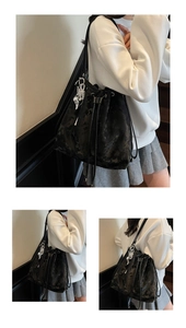 Detail of black drawstring bucket bag with floral texture and silver heart charms
