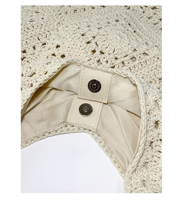 Detail of hand-woven tote bag showing magnetic silver clasp and cream satin lining