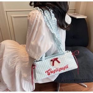 Detail of blue and white checkered handbag with red heart patch and bow on corduroy chair